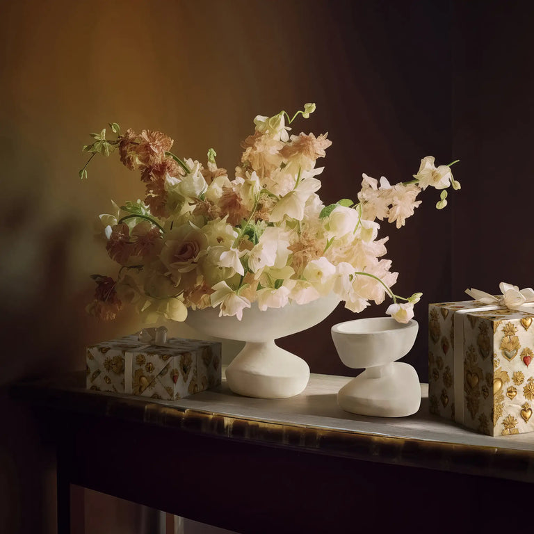 Lemieux et Cie Sacred Heart white and gold wrapping paper wrapping influenced by French devotional art from the 18th century on gift boxes next to a floral arrangement in the Ducoli and Matili bowls