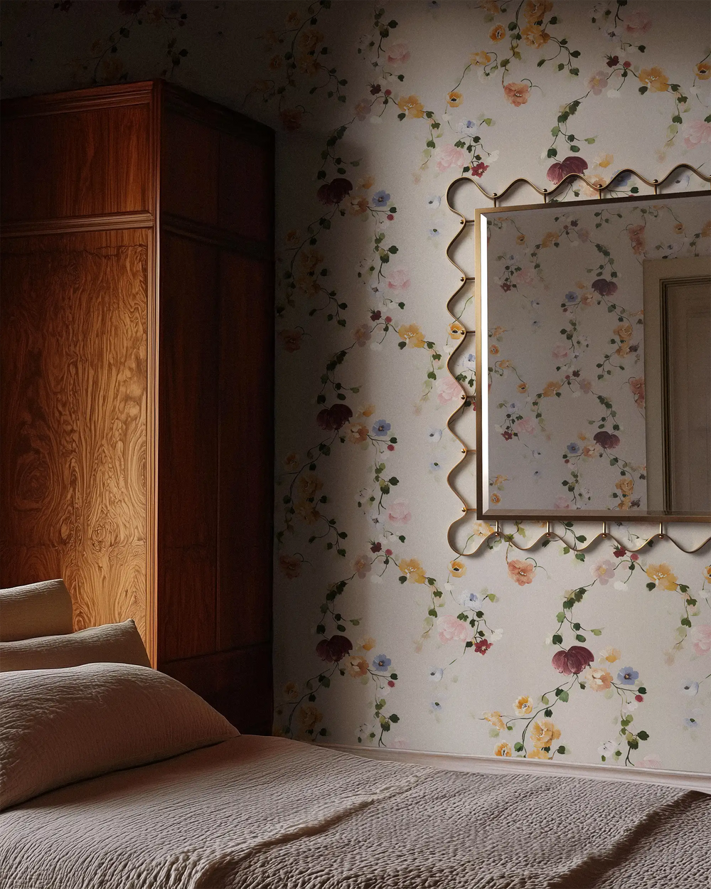 Lemieux et Cie Vine Floral Wallpaper in soft cream with trailing florals in pink, plum and yellow, shown in a bedroom with warm wood wardrobe and textured bedding.