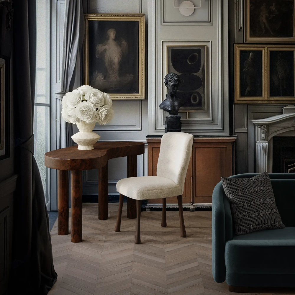Lemieux et Cie Brenne Desk, rounded table with tapered legs, styled with upholstered chair in a sitting room with herringbone wood floors and paneled walls.
