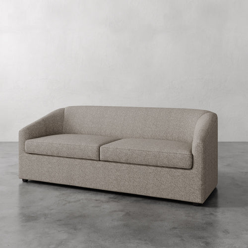 Lemieux et Cie Arvelle Queen Sleeper in neutral tone, low-profile sofa with rounded arms, shown on polished concrete floor against pale plaster walls.