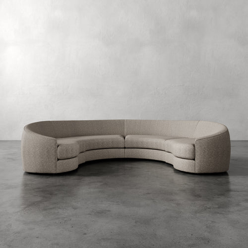 Lemieux Et Cie Rulmann 4-Piece Sectional  Curved beige sofa on a gray floor with a plain gray wall background