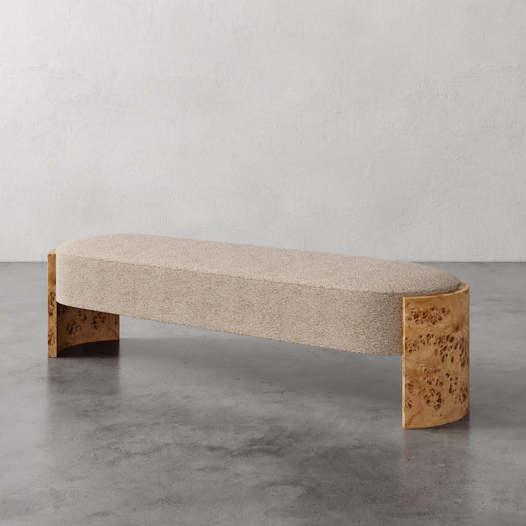 Lemieux et Cie Benoit Bench in textured bouclé upholstery with curved maple burl legs, upholstered bench shown on polished concrete floor against neutral plaster walls.
