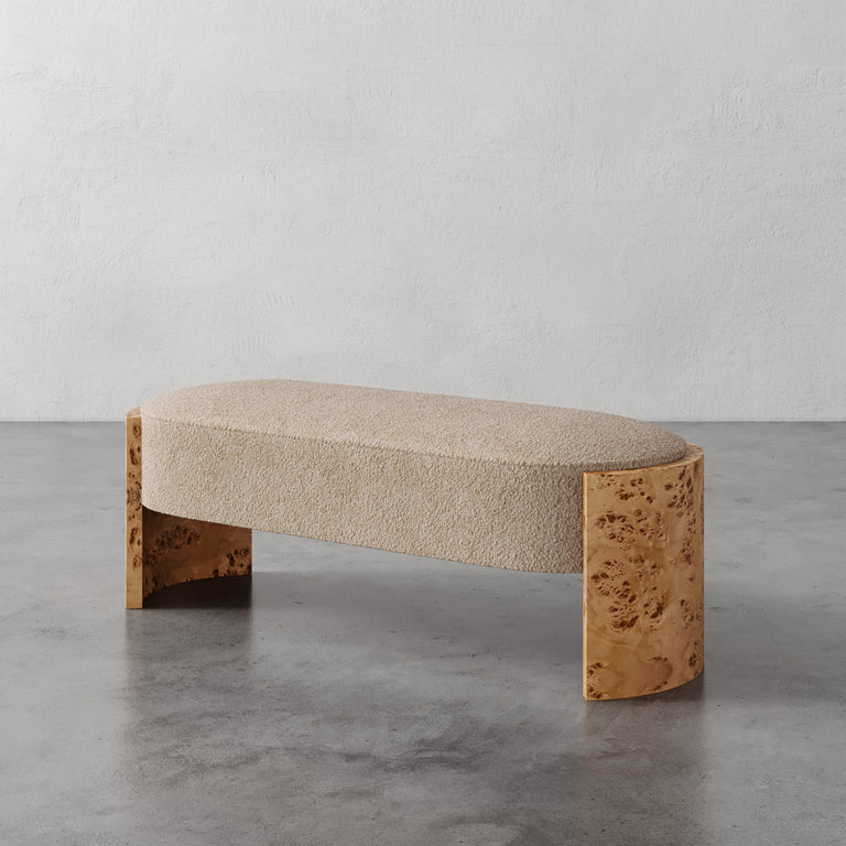 Lemieux et Cie Benoit Bench with curved Maple burl legs and textured upholstered seat, shown on polished concrete floor against neutral plaster walls.