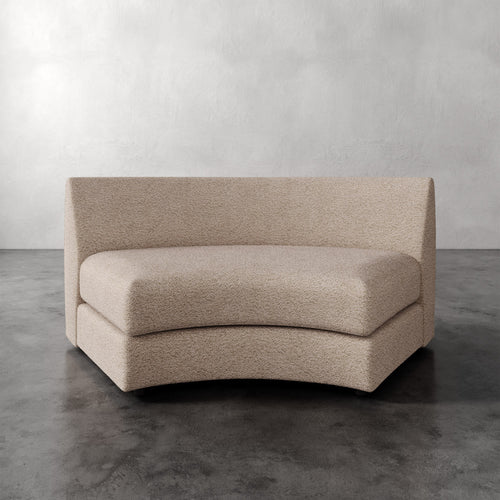 Lemieux Et Cie Rulmann Wedge Beige curved sofa on a gray floor with a neutral background