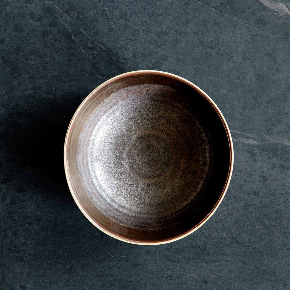 Lemieux et Cie Akita Stoneware Bowl with reactive glaze and copper highlights, ceramic dining bowl shown on dark stone surface.