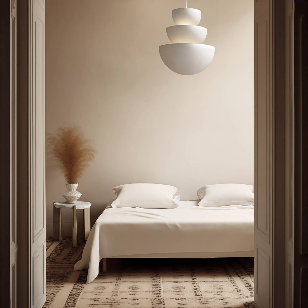 Lemieux et Cie Aline Side Table, cylindrical low-profile form in ivory, bedside with pampas grass and ceramic vase in neutral bedroom with patterned rug.