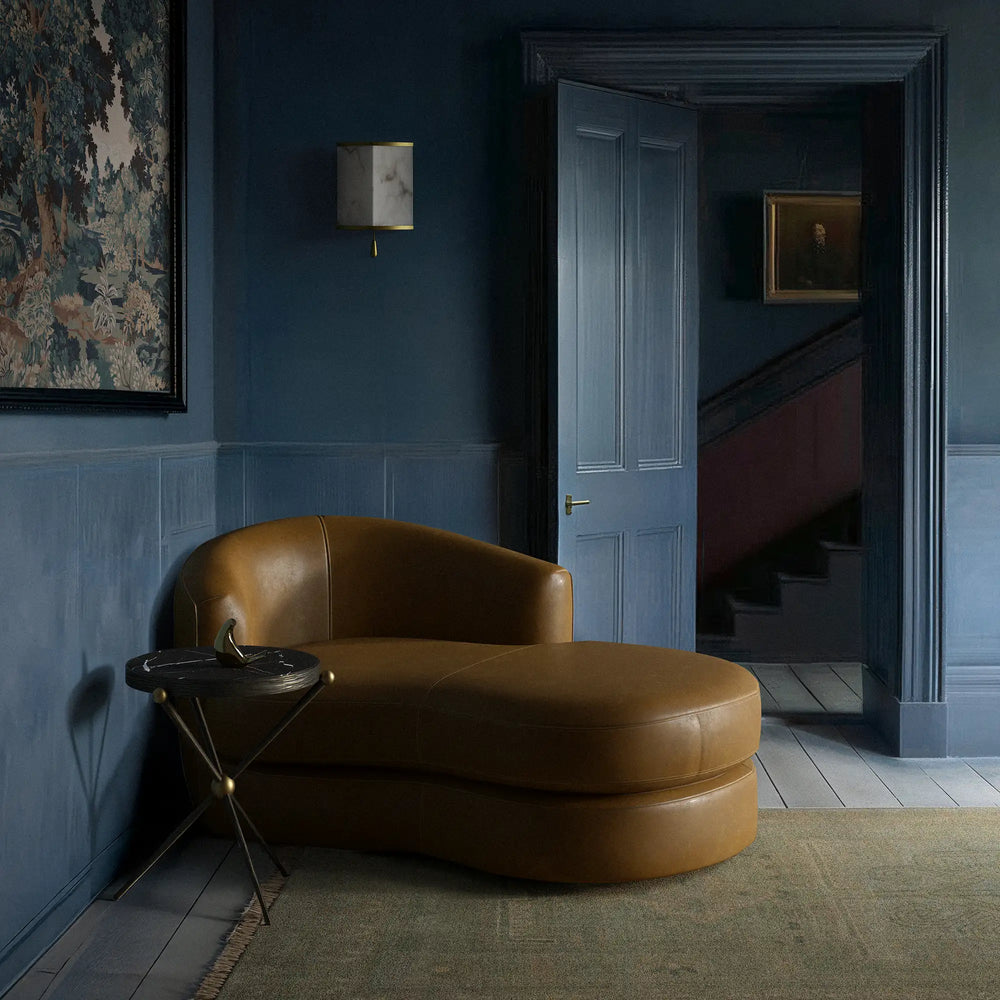 Lemieux et Cie Rulmann Leather Left Arm Chaise in warm tan leather, sculptural modular seating shown in a sitting room with dark blue paneled walls and wood flooring.