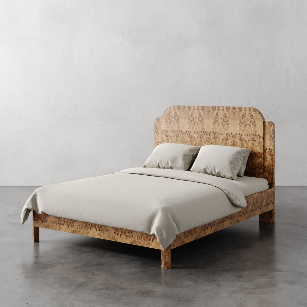 Lemieux et Cie Avenir Bed with figured burl headboard and frame, bed styled with neutral linens on concrete floor against white plaster walls.