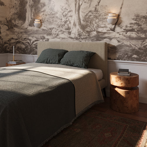 Lemieux et Cie Beaunay Tiered Sconces in cast plaster, a designer lighting fixture, on each side of a bed with an Avenir Side Table on the right in a European-style bedroom.