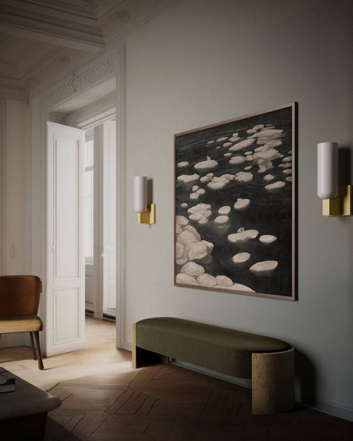 Lemieux et Cie Maroux wall sconce in burnished brass and aged iron with vertical opal glass illumination, styled in a modern interior with a bench, layered wall art.