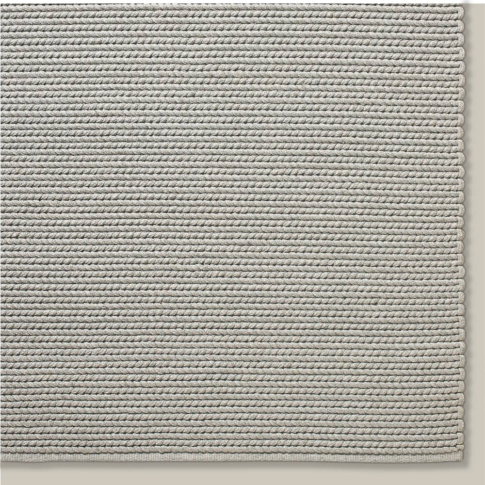 Lemieux et Cie Tricot Handwoven Outdoor Rug in grey, textured handwoven rug with horizontal rope-like rows, shown on neutral studio backdrop.