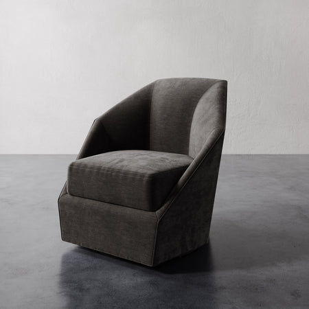 Lemieux et Cie Bijou Swivel Chair in charcoal, sculptural swivel chair with angular geometric silhouette, shown on polished concrete floor against white walls.