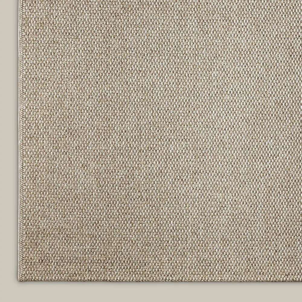 Lemieux et Cie Provence Outdoor Rug in natural, woven textured rug shown on neutral painted floor with diagonal weave pattern.