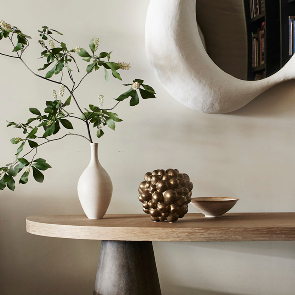 Lemieux et Cie Bubble Vase in bronze, sculptural spherical form with clustered bubble texture, styled on wood console with mirror and greenery against neutral walls.