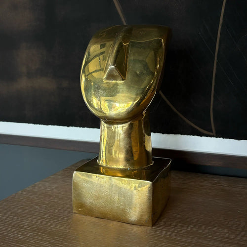 Lemieux et Cie Vintage Art Deco Abstract Brass Bust Sculpture with warm patina, displayed on wood surface beneath dark artwork in soft daylight.