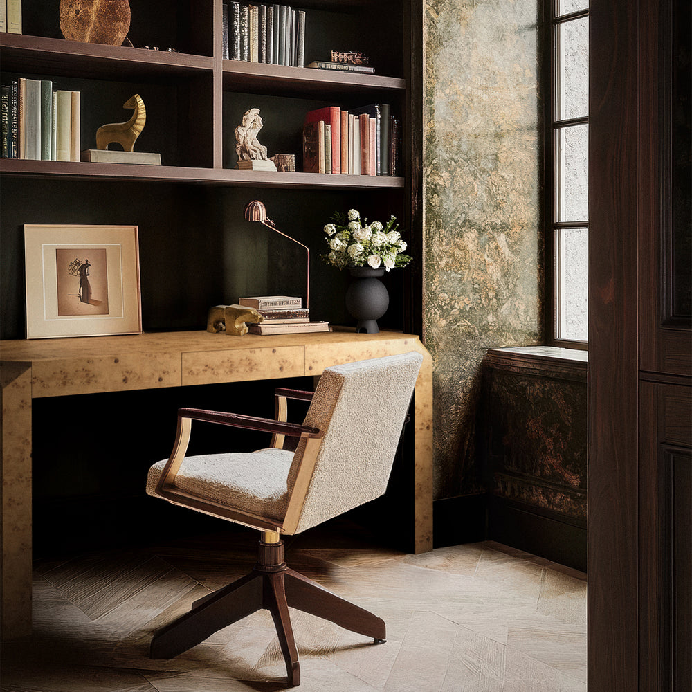 Lemieux et Cie Armand Desk in hand-matched burl veneer, desk at study window with dark shelving, aged plaster walls and wood floors.