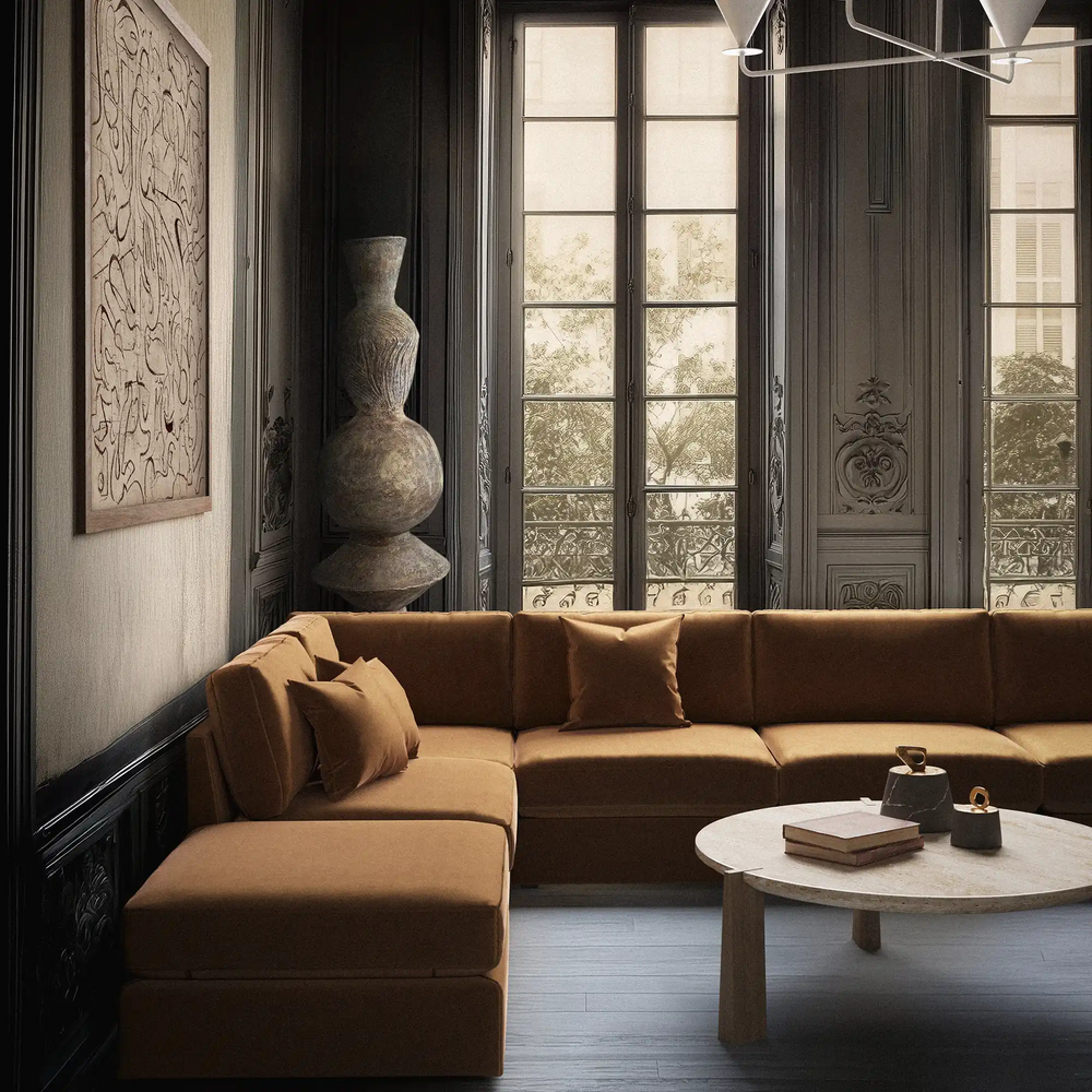 Lemieux et Cie Chanaux 6-Piece Sectional in caramel upholstery, modular sofa in dark wood-paneled room with tall French windows and stone coffee table.