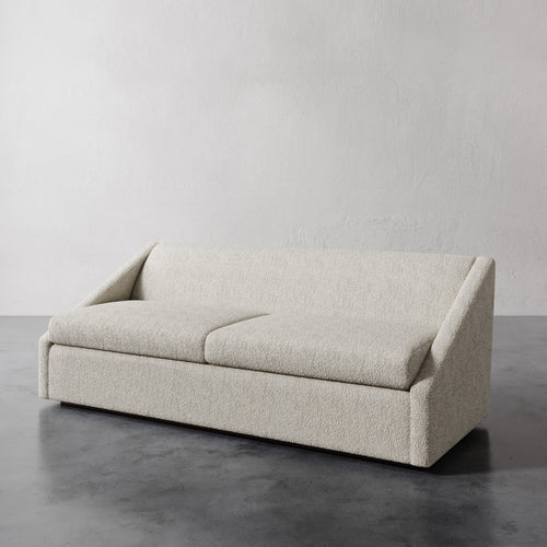 Lemieux et Cie Fontaine Sofa in ivory bouclé, low-profile sofa with architectural arms, shown on polished concrete floor against neutral plaster walls.