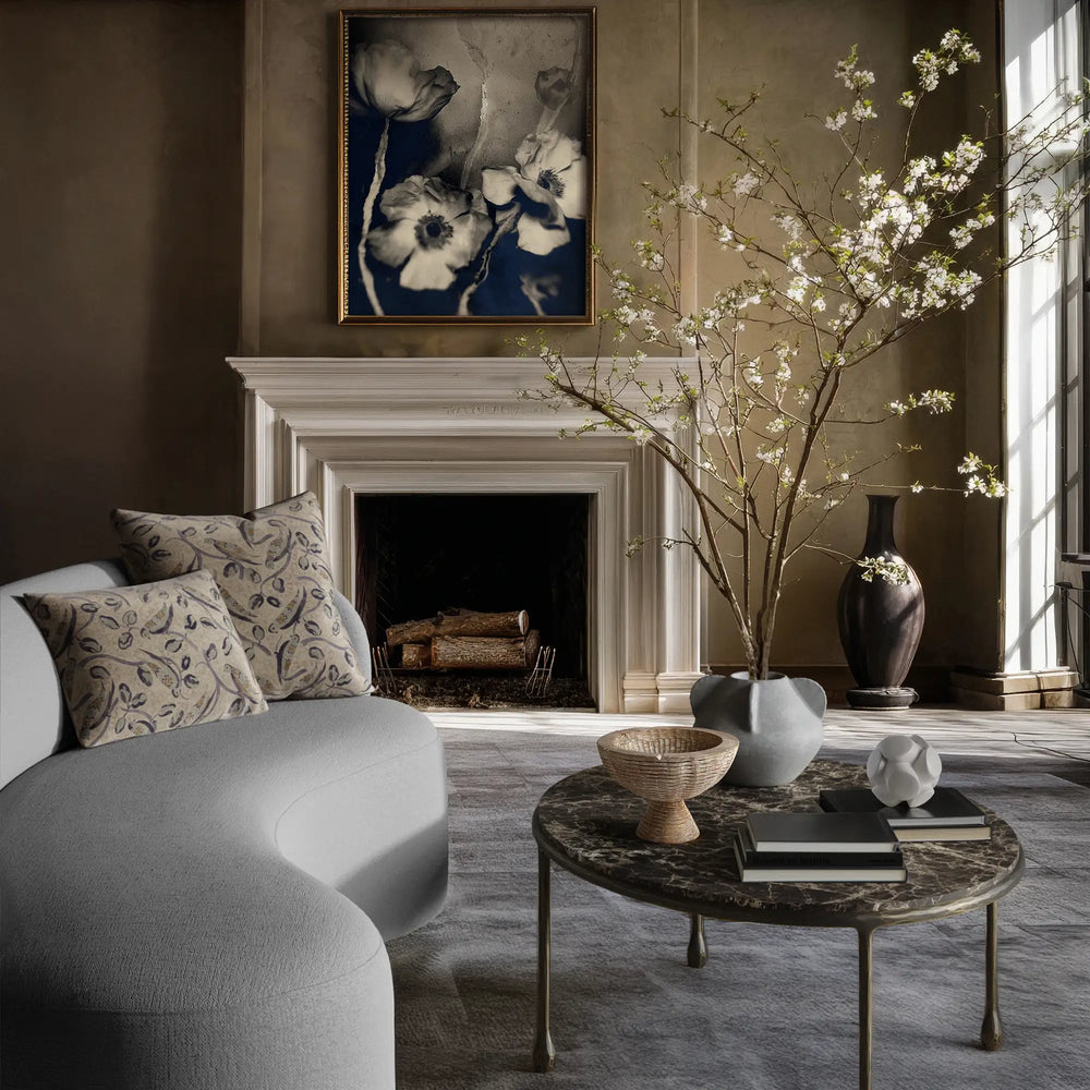 Linen accent pillows with French bird and botanical pattern in indigo, teal, and hazelnut on natural flax ground resting on the Colette sofa, in a living room with the Herbier art print