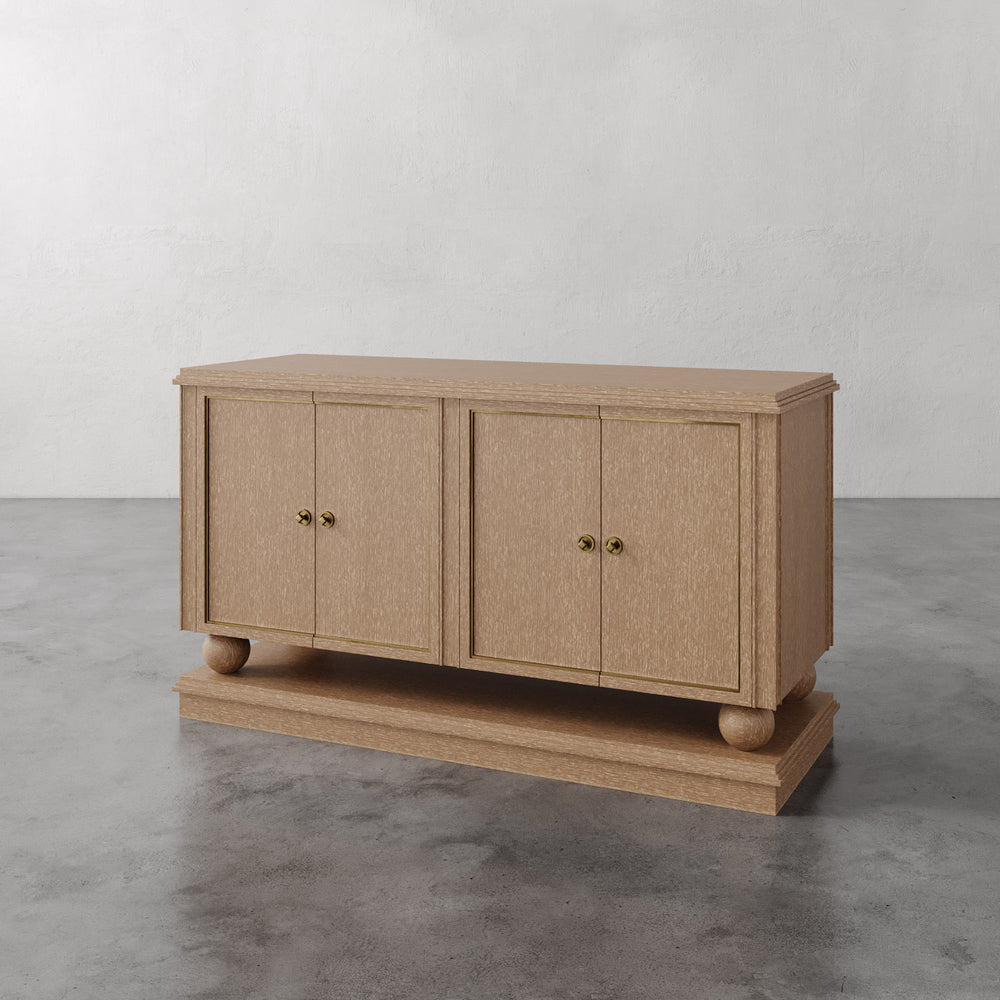 Lemieux et Cie Corvaux Credenza in cerused oak with brass hardware, storage console on polished concrete floor against white textured walls.