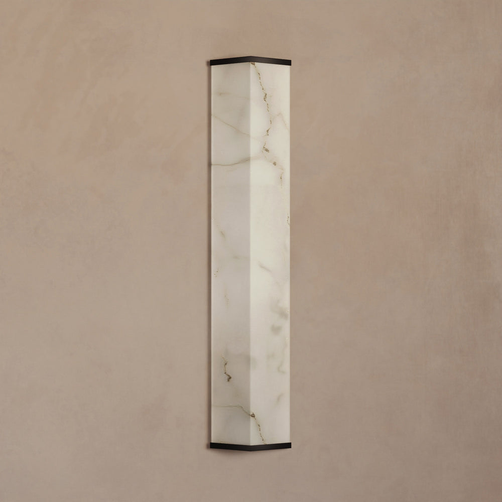 Lemieux et Cie Cleor Large LED Sconce with faux alabaster shade and dark frame, wall sconce shown on warm neutral plaster wall.