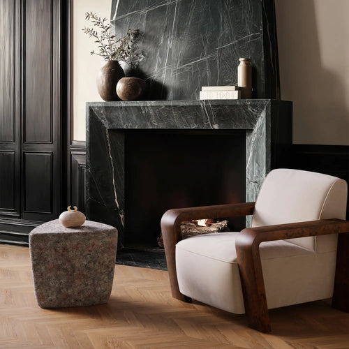 Dumas armchair with the handmade Ember Ash ceramic stool and end table with reactive glaze. Placed in front of a modern marble fireplace.