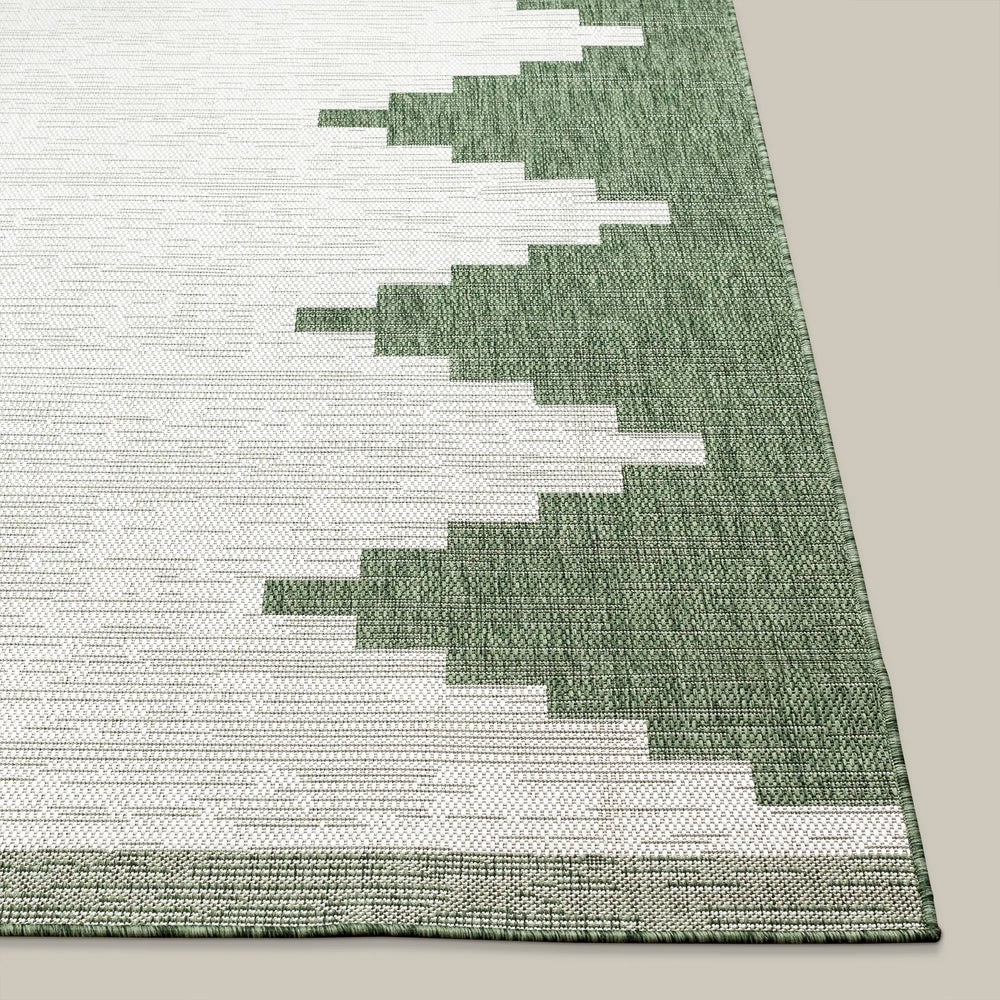 Lemieux et Cie Cottier Outdoor Rug in green and ivory, geometric stepped pattern, woven flatweave construction shown on neutral studio backdrop.