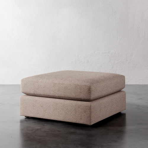Lemieux Et Cie Chanaux Ottoman Beige ottoman on a dark floor with a light gray wall background