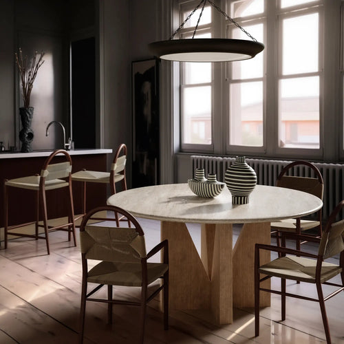 Lemieux et Cie Elysées Dining Table with marble top and geometric base, round dining table surrounded by oak chairs in a light-filled dining room with white walls.