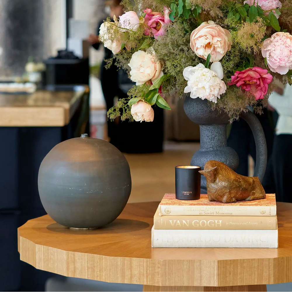 Decorative setup with flowers, sculptures, and books on a wooden table.