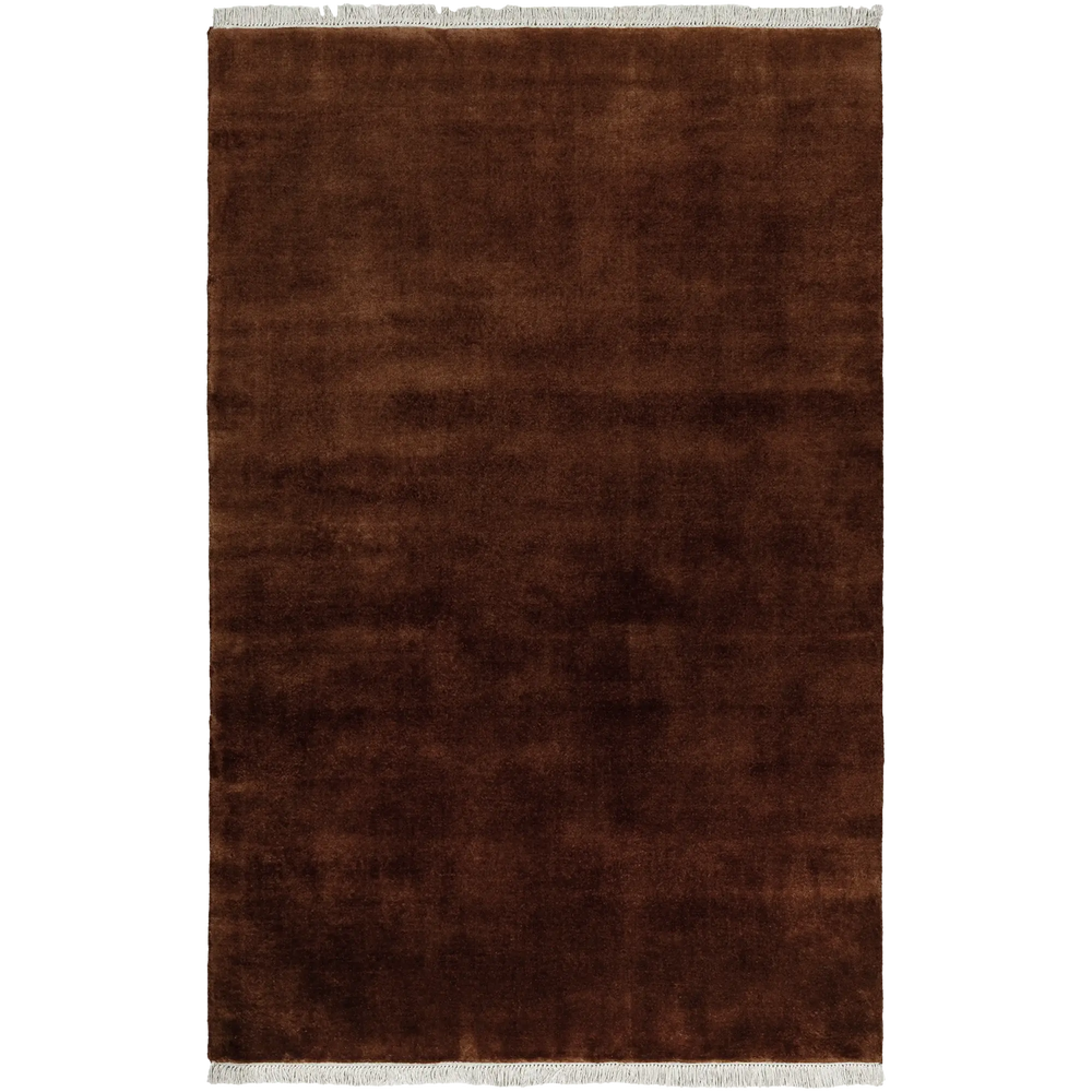 Lemieux et Cie Plume Handmade Wool Rug in oxblood, handloomed solid with fringe detail, shown on white studio backdrop.