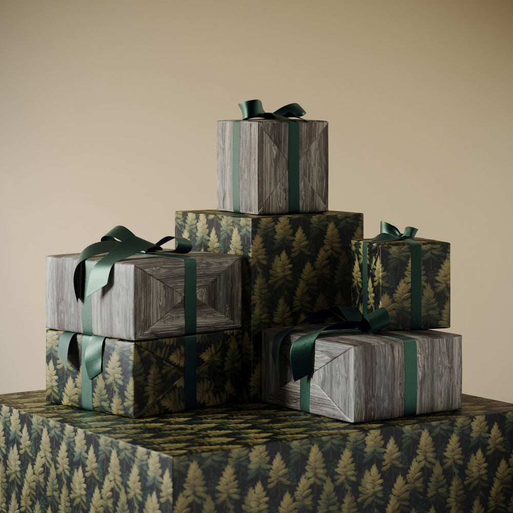 Stack of gifts wrapped in Lemieux et Cie Faux Bois high quality wrapping paper, featuring hand painted woodgrain texture with tonal detail, paired with Forest Evergreen Christmas wrapping paper showcasing stylized evergreen trees in layered green hues.