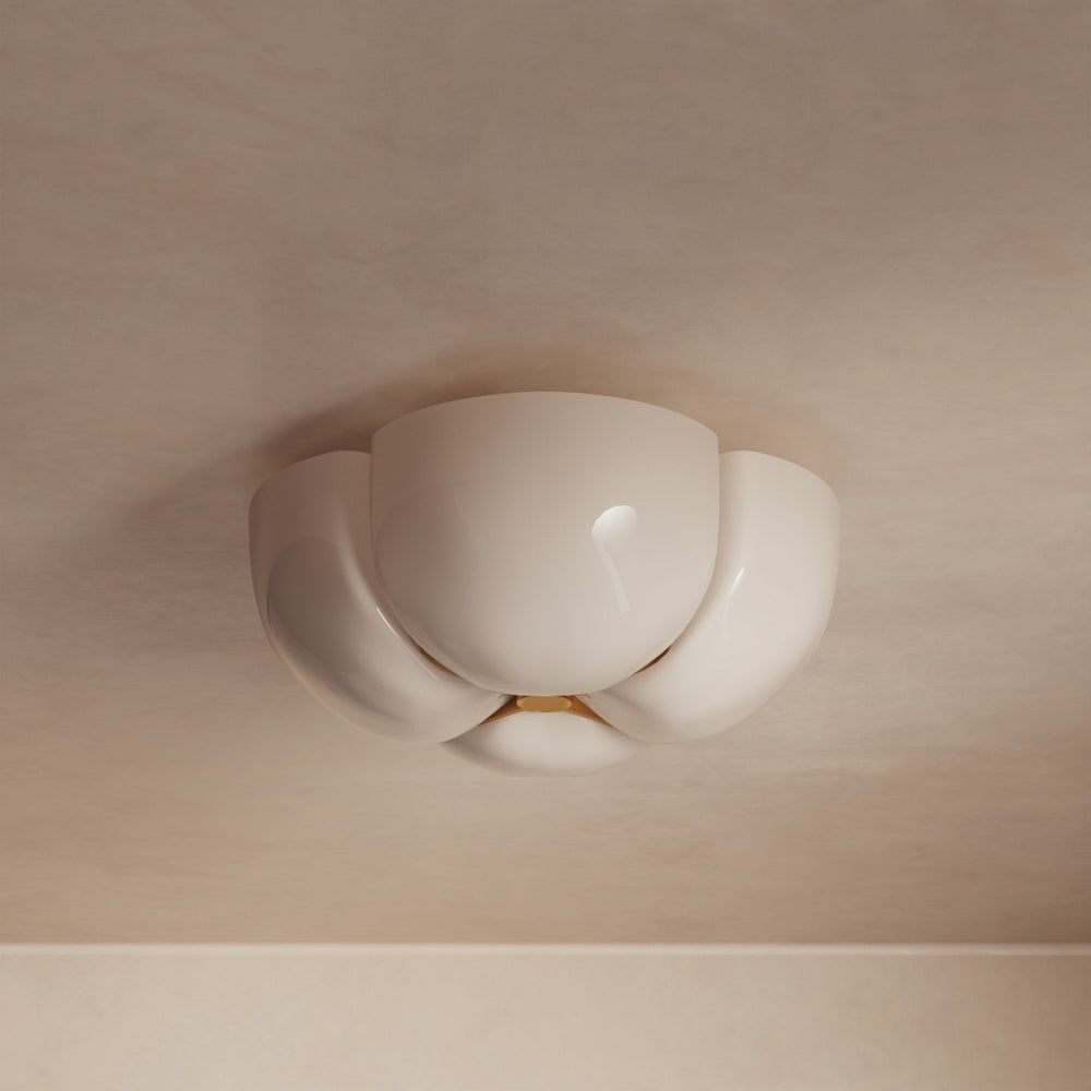 Lemieux et Cie Cheverny ceiling light fixture with sculptural ivory curved shades and warm glow, mounted on neutral ceiling above white wall.