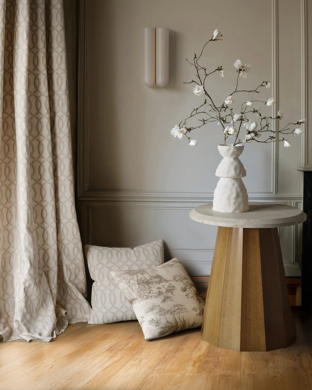 Linen decorative pillow cover with French toile scenic pattern  and gate work pattern drapes in next to the Ondara side table by lemieux et cie