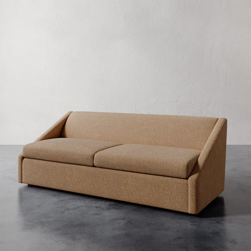 Lemieux et Cie Fontaine Sofa in warm tan upholstery, architectural low-profile sofa with geometric silhouette on dark concrete floor against neutral wall.