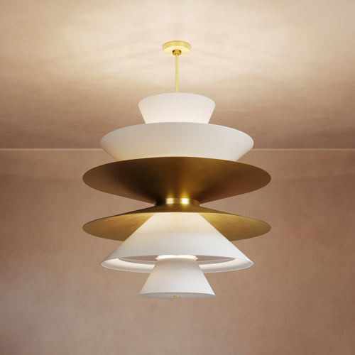 Lemieux et Cie sculptural tiered chandelier with ivory shades and warm brass discs, illuminated pendant shown against neutral plaster ceiling in soft warm light.