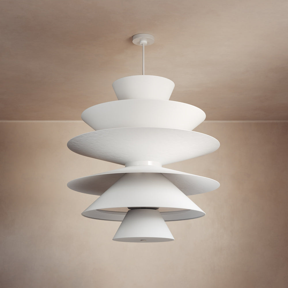 Lemieux et Cie sculptural white chandelier with tiered disc shades, suspended pendant light shown against warm neutral walls in soft atmospheric light.