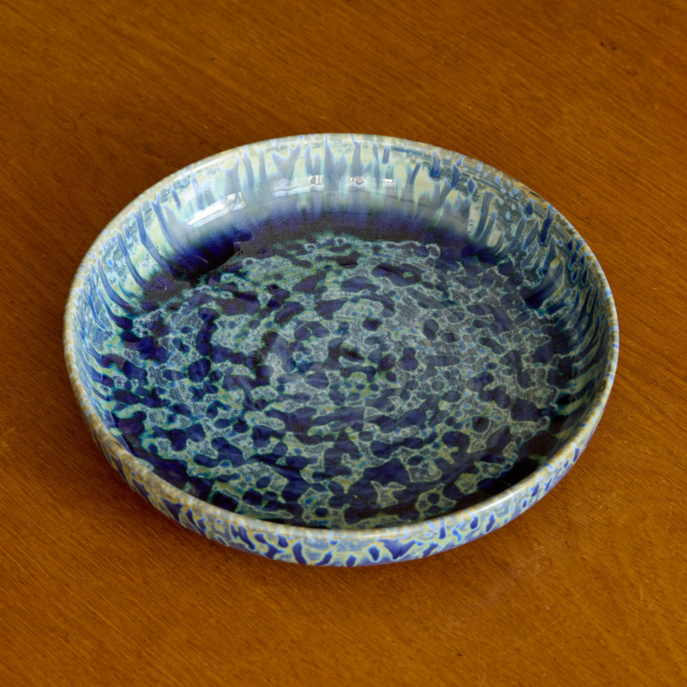 Lemieux et Cie Hanami Stoneware Pasta Bowl in indigo reactive glaze, wide shallow bowl with pooled crackled finish, shown on warm wood tabletop.