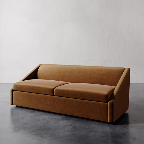 Lemieux et Cie Fontaine Sofa in warm caramel upholstery, low-profile sofa with sculptural arms, shown on polished concrete floor against white plaster walls.