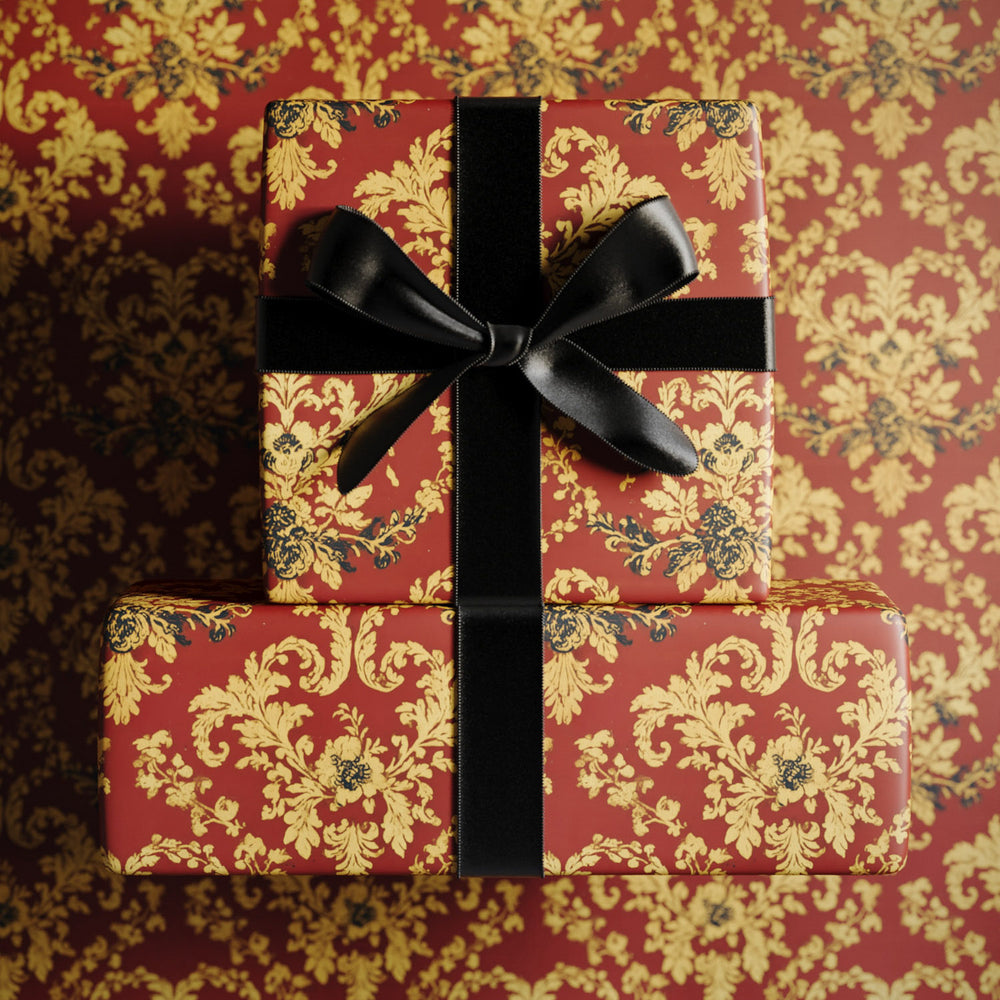Lemieux et Cie Damask Wrapping Paper in deep vermilion with metallic gold patterning, tied with black ribbon, shown against matching damask backdrop.