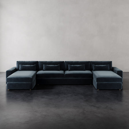 Lemieux et Cie Lacroix U-Sectional in charcoal with dual chaises, low-profile modular sofa on dark concrete floor against neutral plaster walls.