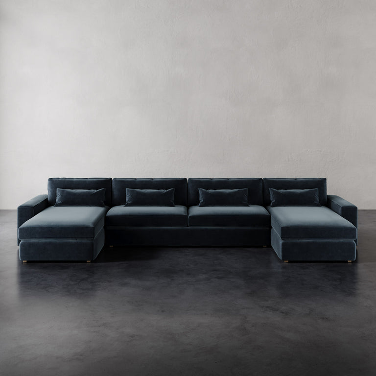 Lemieux et Cie Lacroix U-Sectional in charcoal with dual chaises, low-profile modular sofa on dark concrete floor against neutral plaster walls.