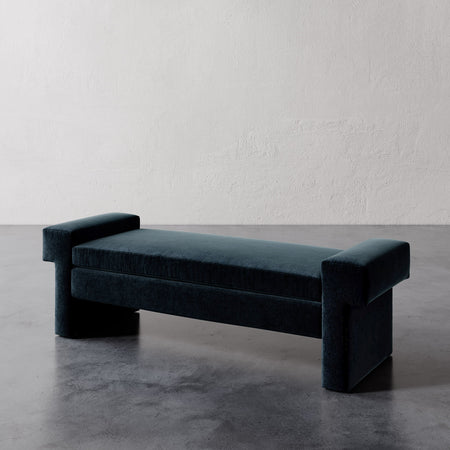 Lemieux et Cie Lemaire Bench in deep teal, upholstered bench with cylindrical bolster arms and wide legs, on polished concrete floor.