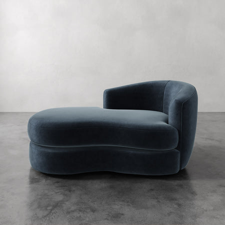 Lemieux et Cie Rulmann Right Arm Chaise in deep teal, sculptural low-slung form with rounded arms, shown on polished concrete floor against plaster walls.