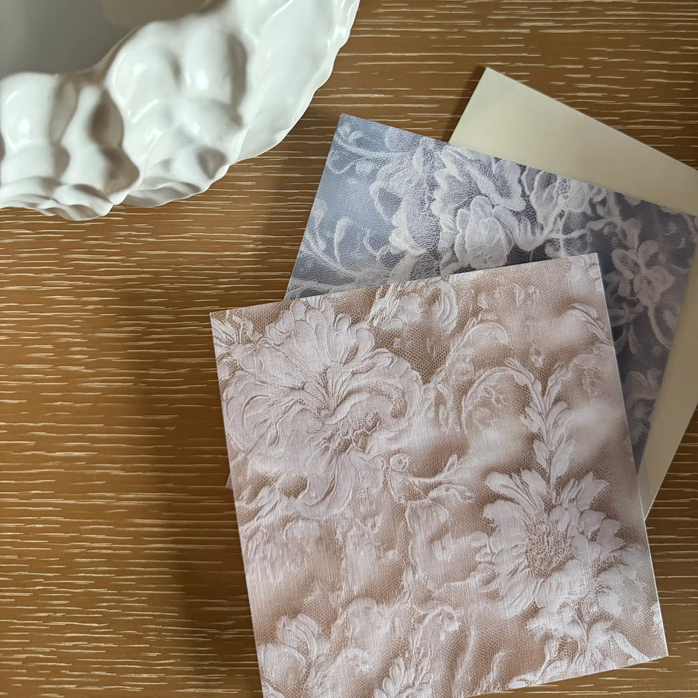 Lemieux et Cie French Lace Greeting Card Set in soft blue, premium linen paper cards with Alençon-inspired floral pattern, arranged on wood surface with sculptural plaster object.