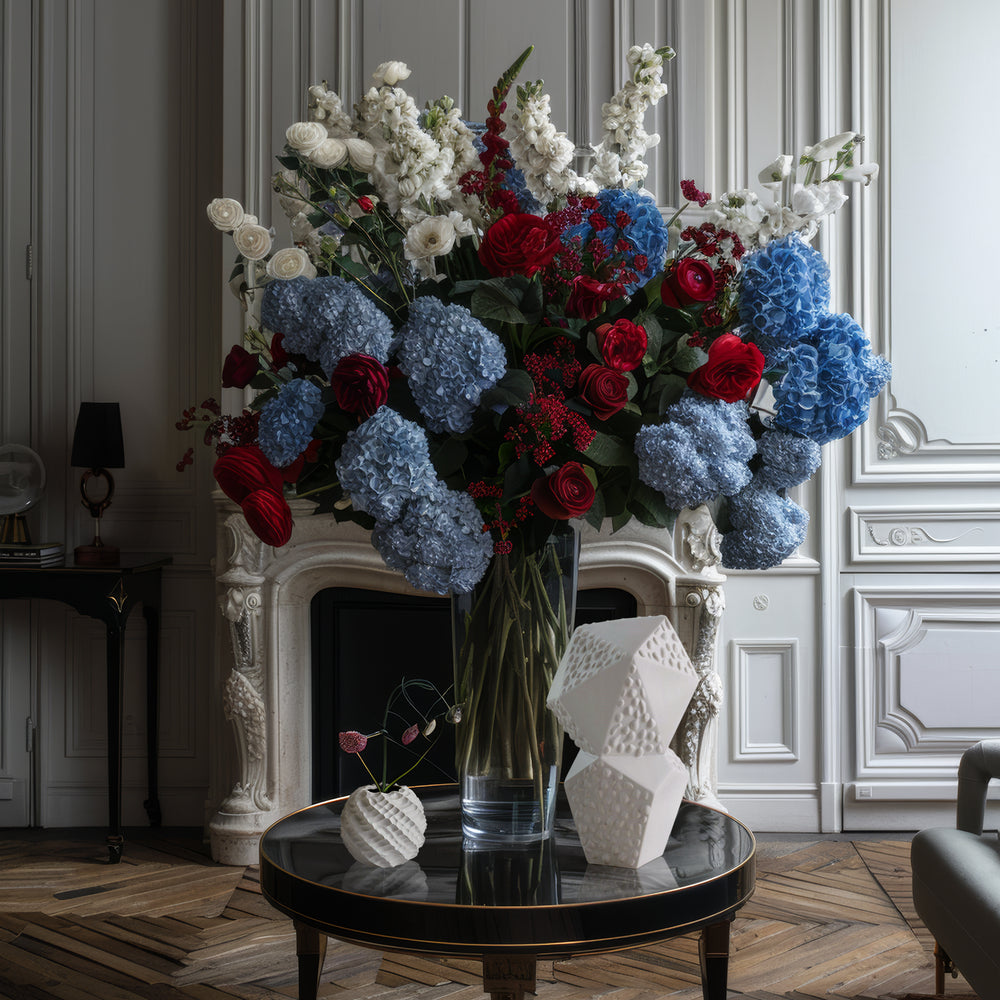Lemieux et Cie textured geometric sculpture in white, sculptural accent piece displayed with blue hydrangeas and red roses on round table in Parisian-style room with herringbone wood floors.
