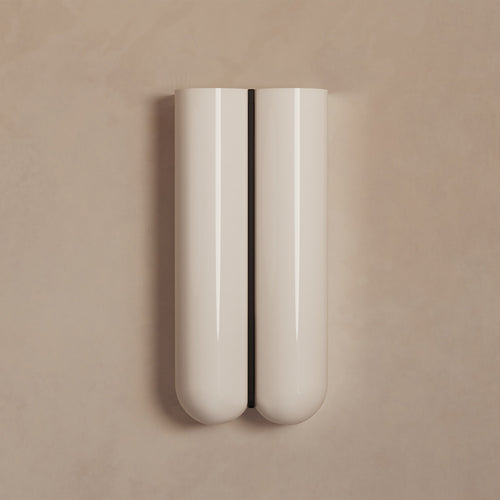Lemieux et Cie Cheverny wall sconce in ivory with sculptural cylindrical form and central dark slot, mounted on neutral plaster wall in soft light.