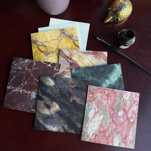 Lemieux et Cie Rosa Portogallo Greeting Card Set, marble-patterned stationery in varied colorways with veining detail, styled on dark wood surface with brass bird and ink bottle