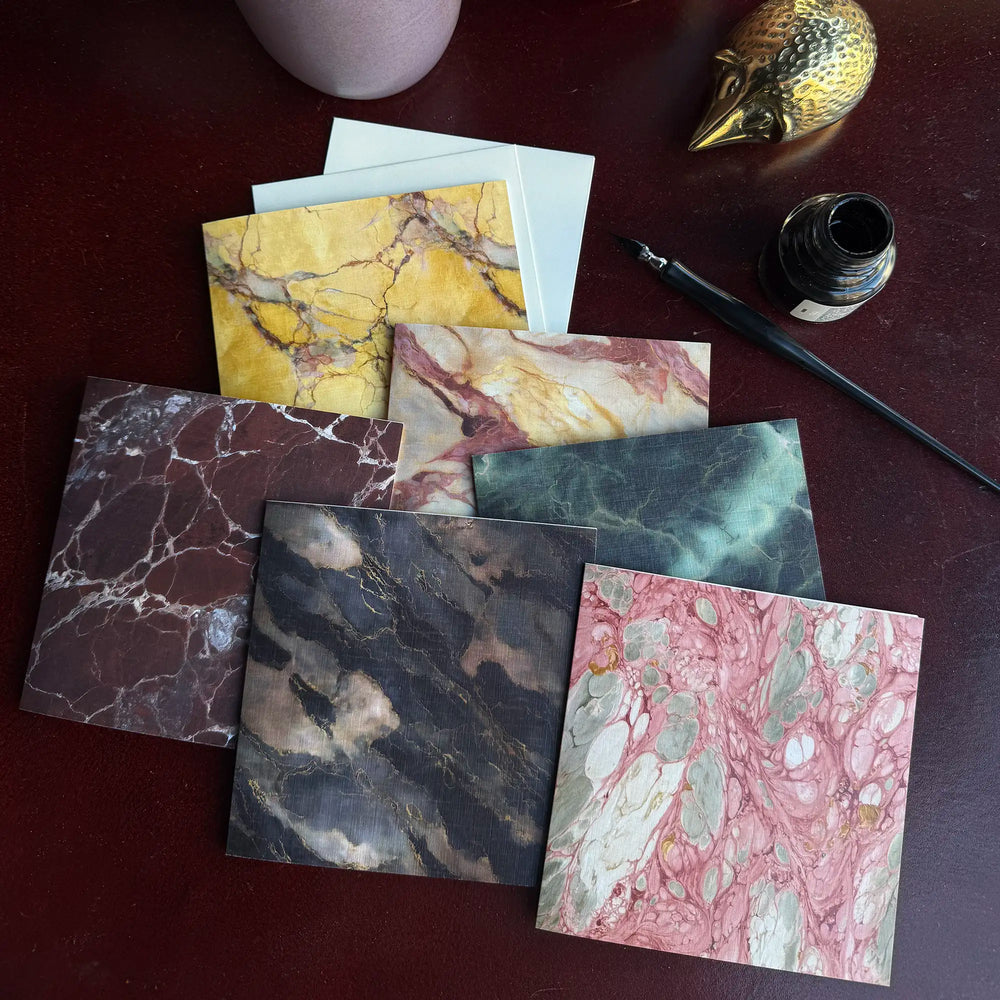 Lemieux et Cie Rosa Portogallo Greeting Card Set, marble-patterned stationery in varied colorways with veining detail, styled on dark wood surface with brass bird and ink bottle