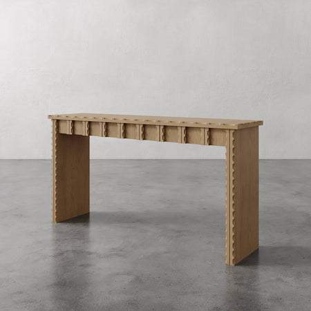 Lemieux et Cie Marchand Console Table in warm oak with scalloped edge detailing, console table on polished concrete floor against neutral plaster walls.